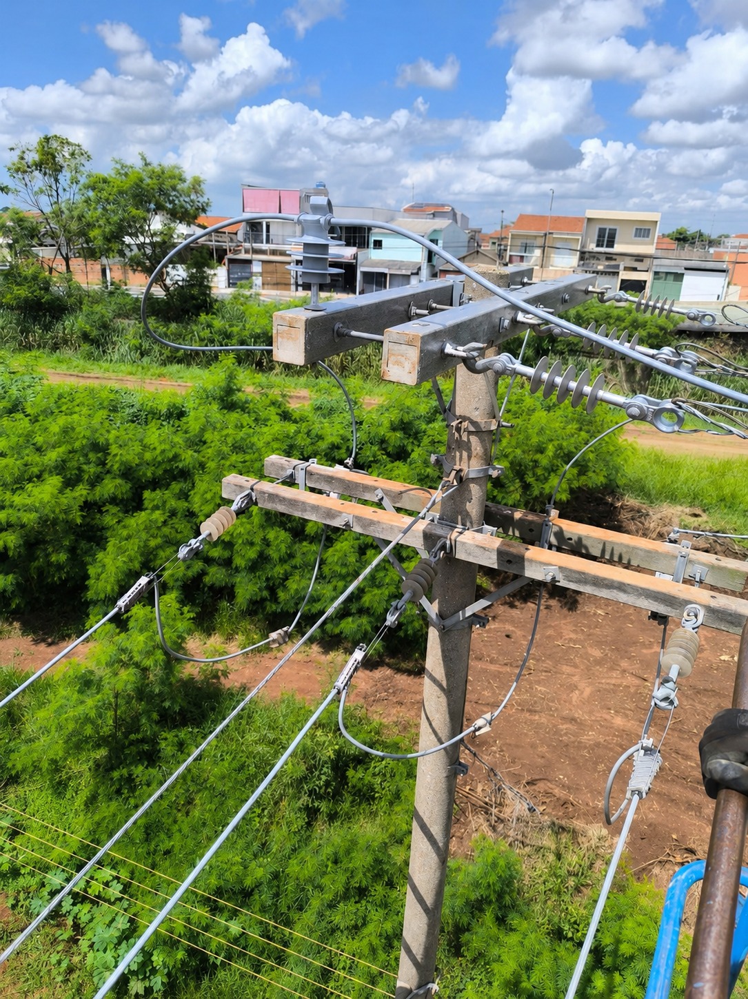 Poste de rede elétrica aérea com isoladores, cabos e chave instalados em área externa