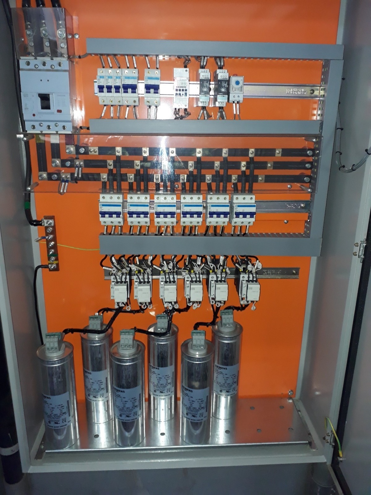 Banco de capacitores instalado em painel elétrico com disjuntores, contatores e barramento